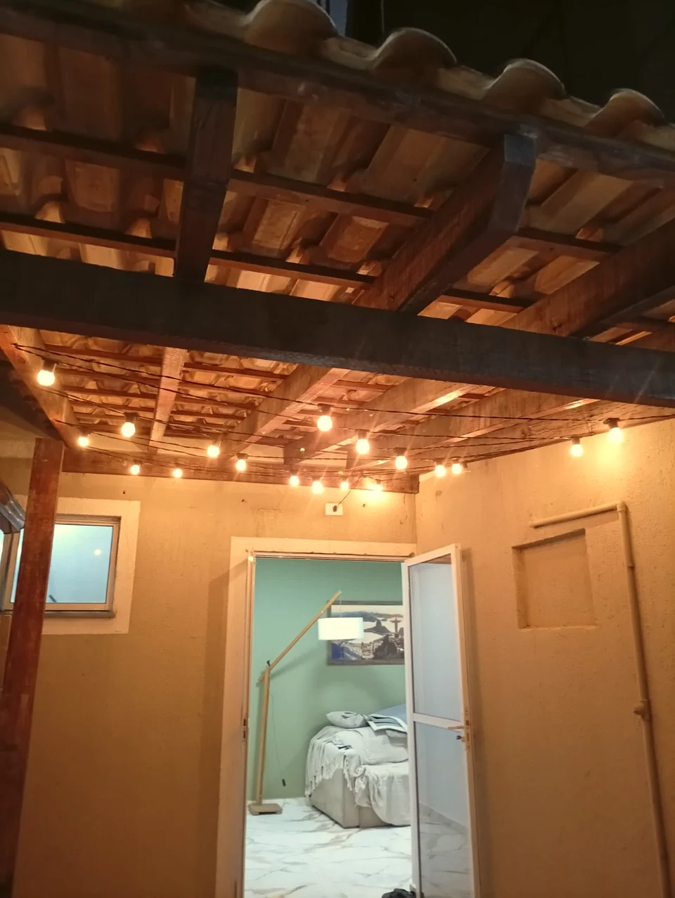 Obra da JBT com madeira aparente, telhas cerâmicas e luzes sob a cobertura